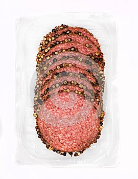 Salami with black pepper in slices, isolated. Meat cold cuts on white background. Packshot photo for package design.