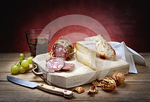 Salami, cheese, bread, grapes, walnuts and glass of red wine