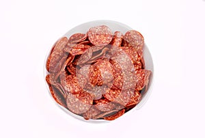 Salami chips, meat snacks in a bowl, isolated. Salami slices, top view, close-up. Packshot photo for package design.