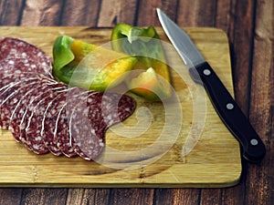 Salami and paprika on wooden chop plate