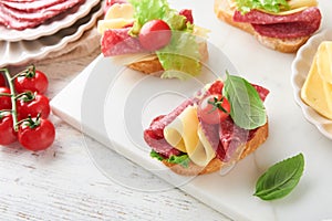 Salami sandwich. Delicious toasted sandwiches with slice salami, cheddar cheese lettuce and tomatoes cherry on white marble