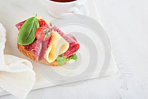 Salami sandwich. Delicious toasted sandwiches with slice salami, cheddar cheese lettuce and tomatoes cherry on white marble