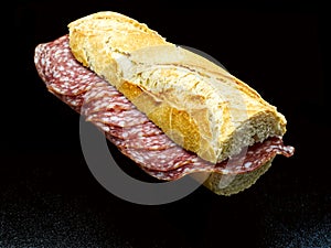 Salami sandwich, panino al salame, baguette and salami, isolated on black background