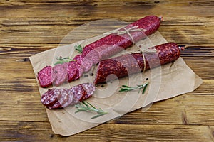 Salami sausages on craft paper on wooden table