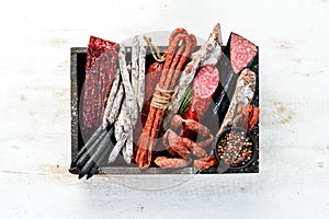 Salami, sausages, spices and meat products in a wooden box. Top view.