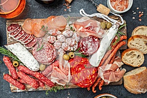 Salami, sliced ham, sausage, prosciutto, bacon, toasts, olives. Meat antipasto platter and red wine, Food recipe background. Close