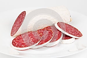 Salami slices on a white plate close-up, pork sausage