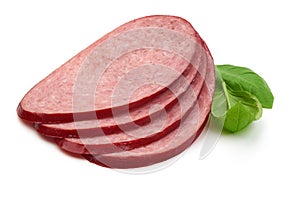 Salami smoked sausage slices with green basil leaves, isolated on white background