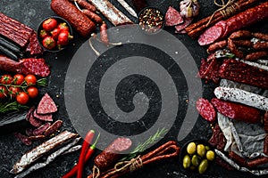 Salami and snacks. Sausage Fouet, sausages, salami, paperoni, on a black stone background. Top view.