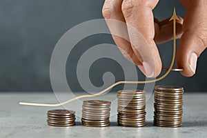 Salary increase concept. Woman stacking coins on grey table and illustration of up arrow photo