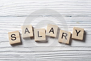 SALARY word written on wood block at wooden background.