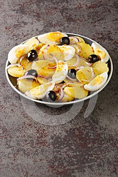 Salata orientala potato salad with onions, olives and boiled eggs close-up on a plate. Vertical