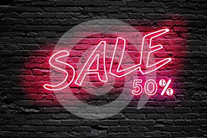 SALE 50 % Percent. fluorescent Neon tube Sign on dark brick wall. Front view. Can be used for online banner ads or background.