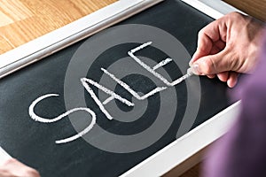 Sale blackboard banner in store, shop or marketplace to promote bargain prices or clearance. Small business owner, salesman.