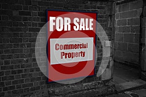 For sale with commercial property written on a sign attached to a wall