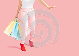 Sale and consumerism concept-Part body,Low Section Of Woman Holding Shopping Bag Against Pink Background