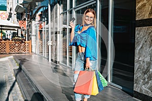 Sale, consumerism, money and people concept - happy young woman with shopping bags and credit card in mall