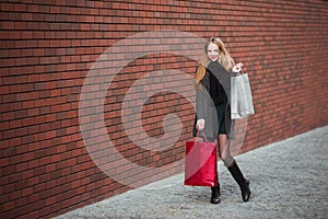 Sale, consumerism and people concept - happy young beautiful women holding shopping bags, walking away from shop.