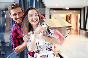 Sale, consumerism and people concept - happy young couple with shopping bags walking in mall.