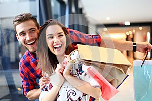 Sale, consumerism and people concept - happy young couple with shopping bags walking in mall.