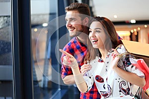 Sale, consumerism and people concept - happy young couple with shopping bags walking in mall.