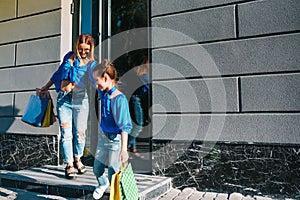 sale, consumerism and people concept - happy young women her dauther with shopping bags walking city street