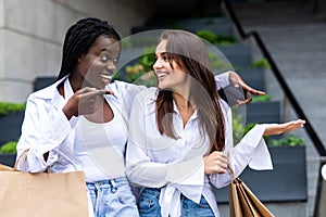 Sale, consumerism and people concept. Happy young women looking into shopping bags at in city