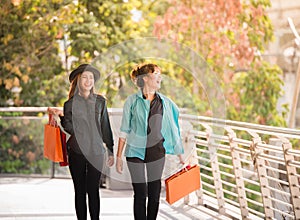 Sale, consumerism and people concept - happy young women looking into shopping bags at shop in city