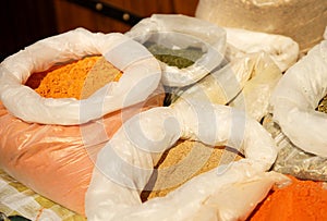 Sale of friable cereals and seasonings in open bags on a bazaar counter. Trade in cereals and medicinal herbs of traditional