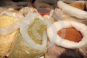 Sale of friable cereals and seasonings in open bags on a bazaar counter. Trade in cereals and medicinal herbs of traditional