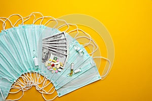 Sale of medical masks. Protective medical mask and different types of pills next to money on yellow background