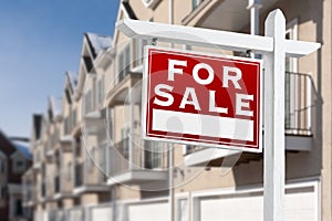 For Sale Real Estate Sign In Front of a Row of Apartment Condominiums Balconies and Garage Doors