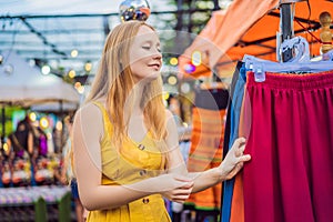 Sale, retail, shopping and clothing concept - Woman chooses clothes in the Asian market