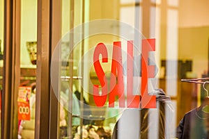 A Sale sign on glass wall outside a clothing store or apparel shop