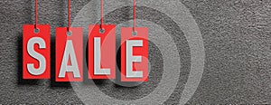 Sale text on red price labels hanging on gray wall background. 3d illustration