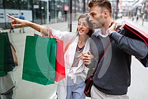 Sale, travel love consumerism and people concept. Happy couple with shopping bags in the city