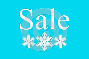 Sale and white snowflakes on a blue background, top view. Background for Christmas, new year, and winter sales. Seasonal discounts