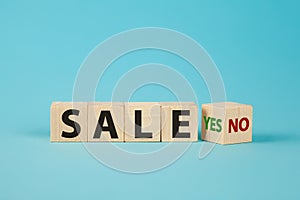 Sale word no to yes. Hand turns a dice and changes the word no to yes. On sale Cubes dice with Sale Yes or No on wooden