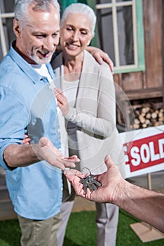 Saleman giving keys of new house to happy senior couple photo