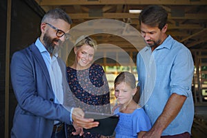 Sales Agent showing plans of new house to young family on construction site.