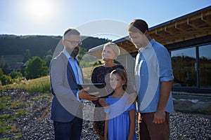 Sales Agent showing plans of new house to young family on construction site.