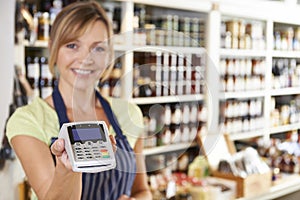 Sales Assistant In Food Store Handing Credit Card Machine To Cus