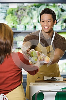 Sales assistants handing packets of apples