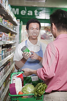 Sales clerk assisting man in supermarket, Beijing