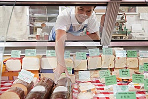 Sales Clerk reaching in to get cheese at Deli counter