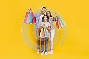 Sales Concept. Happy caucasian family of three holding shopping bags and smiling