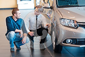 Sales consultant points to the wheel of car