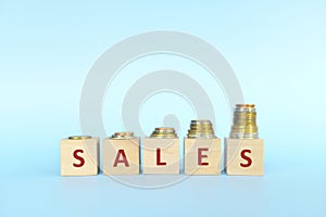 Sales increase business concept. Wooden blocks typography with increasing stack of coins.