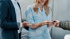 Sales manager giving car key to young caucasian woman