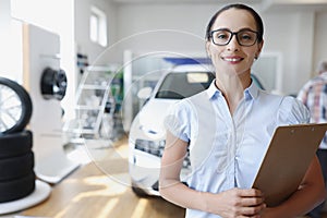 Sales manager holding clipboard in car showroom